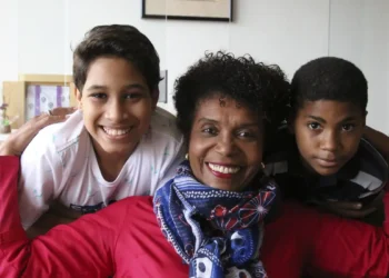 Imagem de uma mulher com dois filhos sorrindo.