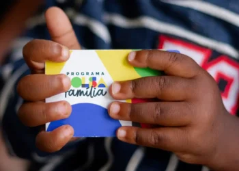 Imagem da mão de uma criança segurando o cartão do Bolsa família.