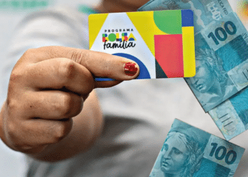Imagem de uma mulher segurando o cartão do Bolsa família