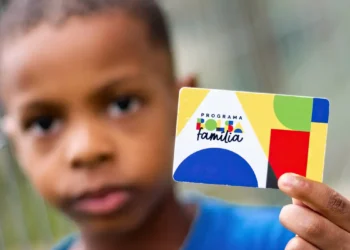 Imagem de um garoto beneficiário do Bolsa Família segurando um cartão