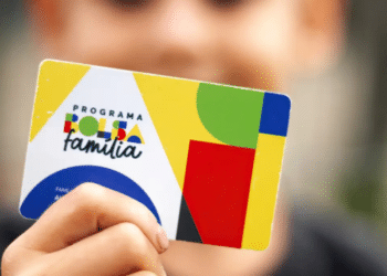 Cartão do Programa Bolsa Família segurado por uma pessoa, representando benefícios sociais para famílias de baixa renda no Brasil.