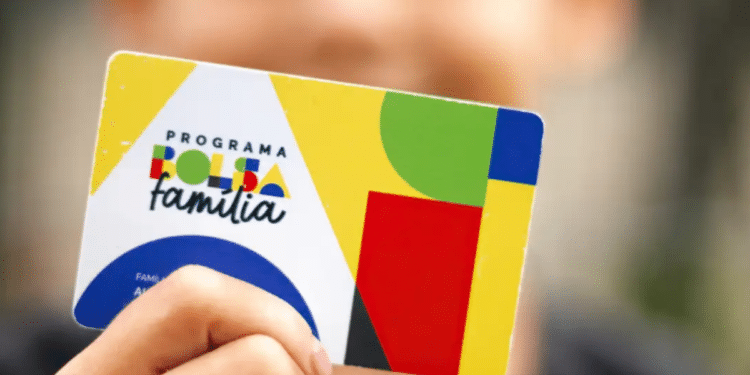 Cartão do Programa Bolsa Família segurado por uma pessoa, representando benefícios sociais para famílias de baixa renda no Brasil.