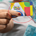 Cartão do programa Bolsa Família sendo segurado, com dinheiro em reais ao fundo, e imagem com aviso de bloqueio ou suspensão do benefício.