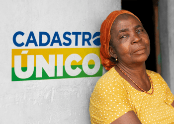 Mulher ao lado de uma parede com o logotipo do Cadastro Único