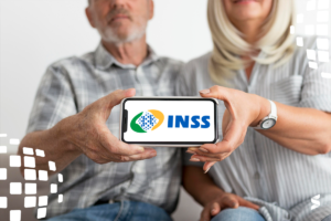 Casal de idosos segura celular com o logo do INSS, representando o calendário de pagamentos.