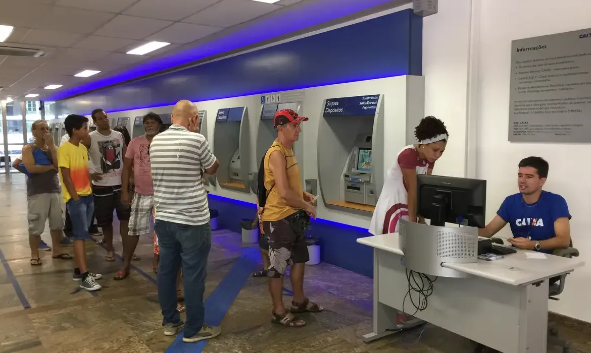 Pessoas aguardando na fila para realizar o saque do PIS/PASEP em uma agência da Caixa Econômica.