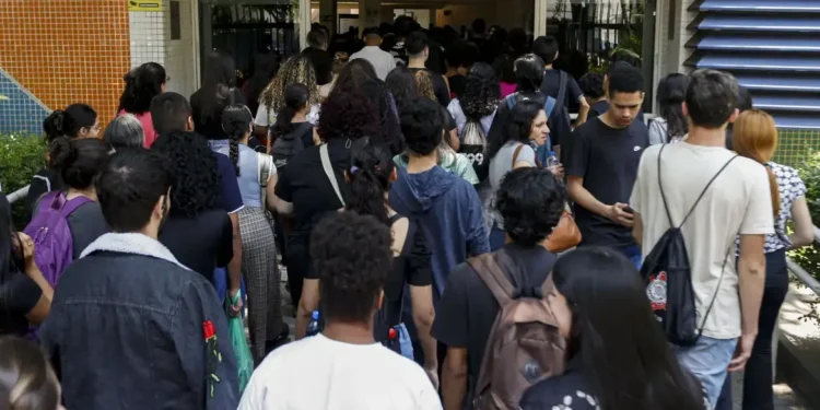 Estudantes entrando em um prédio lotado no primeiro dia de aulas.