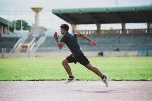 Jovem atleta correndo na pista de atletismo, simbolizando o esforço e a dedicação no treinamento esportivo.