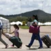 Famílias de imigrantes brasileiros retornando ao Brasil, com malas e bolsas.