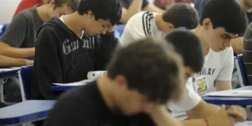 Estudantes em sala de aula realizando prova, simbolizando o contexto educacional.