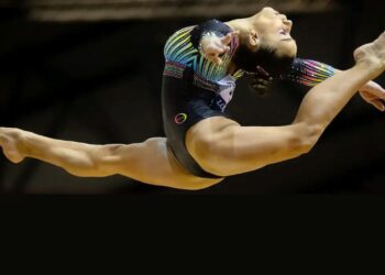 Atleta de ginástica saltando em competições, representando o Programa Bolsa Atleta.