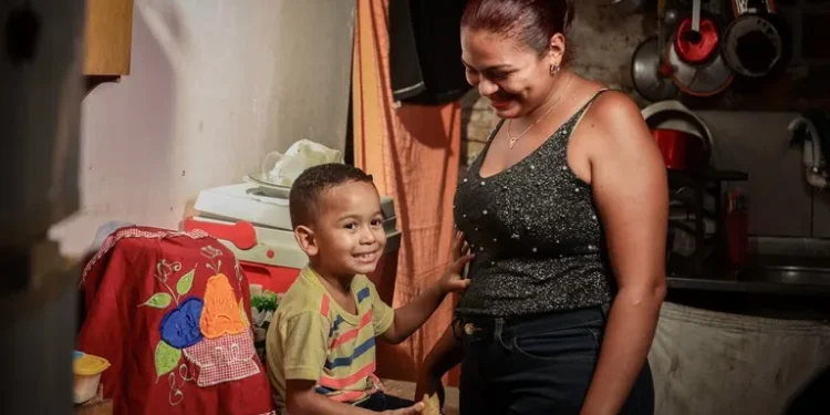 Mãe e filho sorrindo em uma cozinha simples, representando o impacto do Bolsa Família.