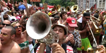 Bloco de Carnaval com músicos e foliões celebrando nas ruas.