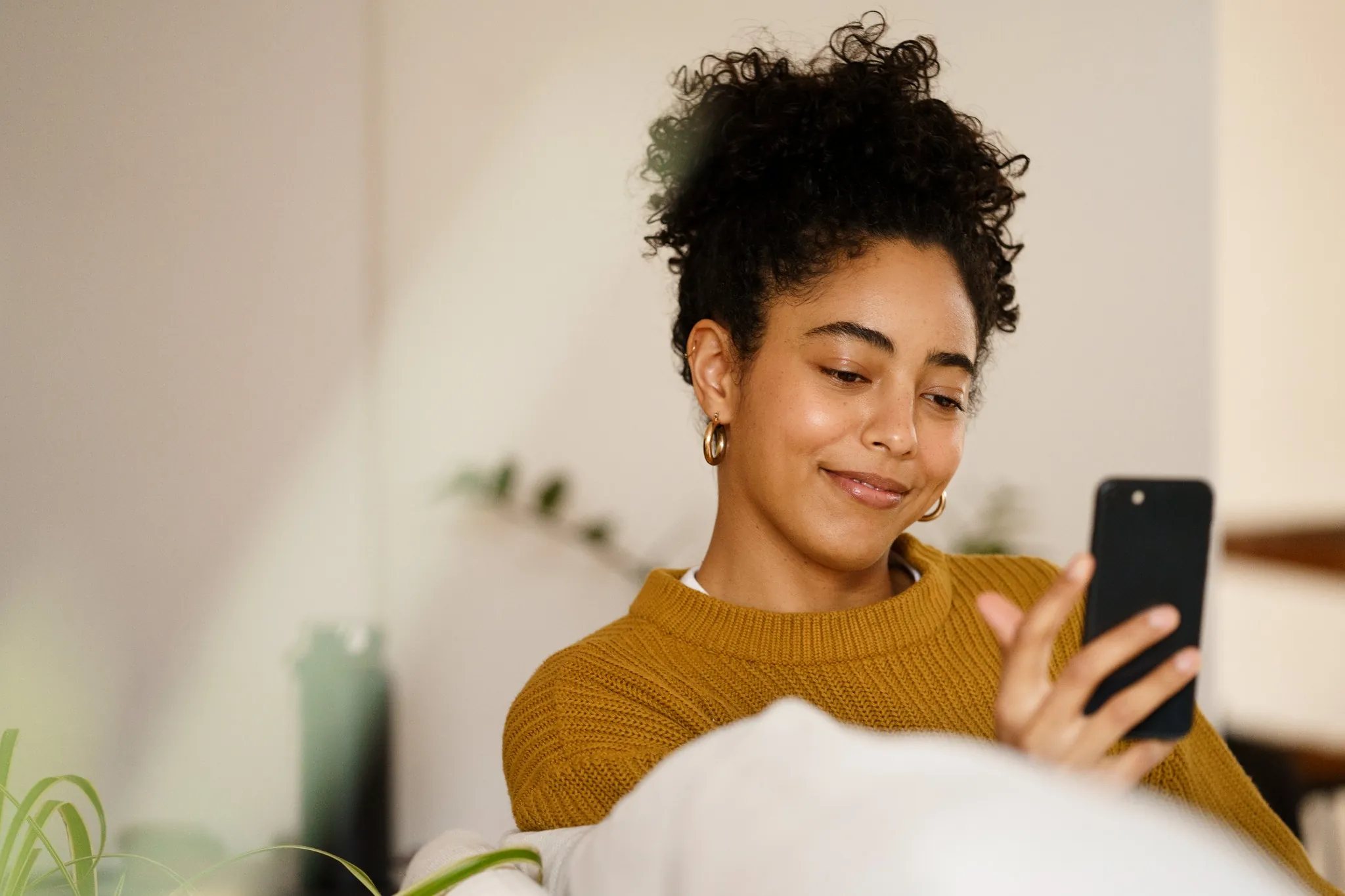 Mulher sorridente usando o celular para verificar informações online.