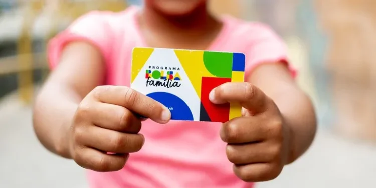 Criança segurando um cartão do Programa Bolsa Família com um sorriso.