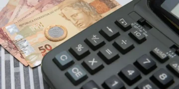 Imagem de uma calculadora com dinheiro do lado