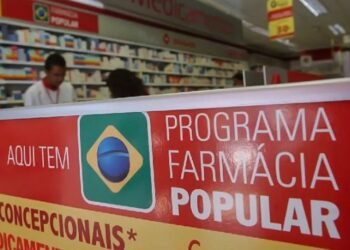 Fachada da Farmácia Popular com banner informativo sobre medicamentos gratuitos.