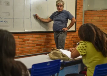Aula de ensino com professor explicando no quadro branco.