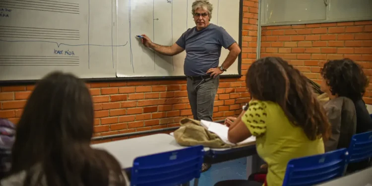Aula de ensino com professor explicando no quadro branco.