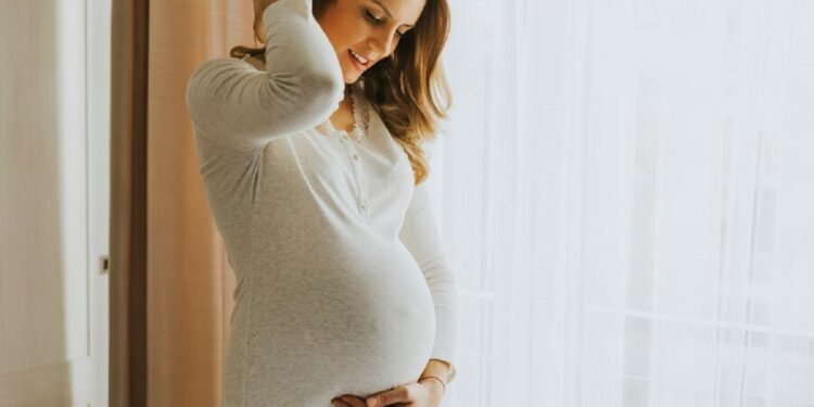 Mulher grávida em uma pose descontraída, representando a elegibilidade para o salário-maternidade.