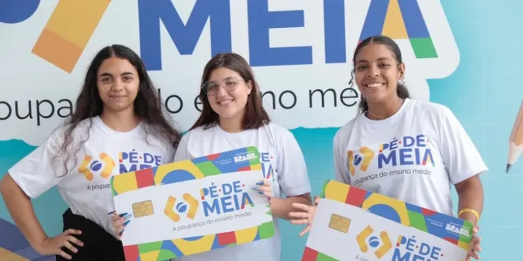 Três jovens seguram cartões representativos do programa Pé-de-Meia em um evento oficial.