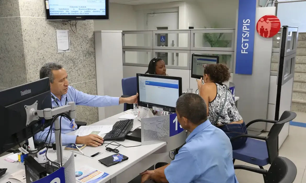 Atendimento em agência bancária, com funcionários auxiliando clientes no balcão.