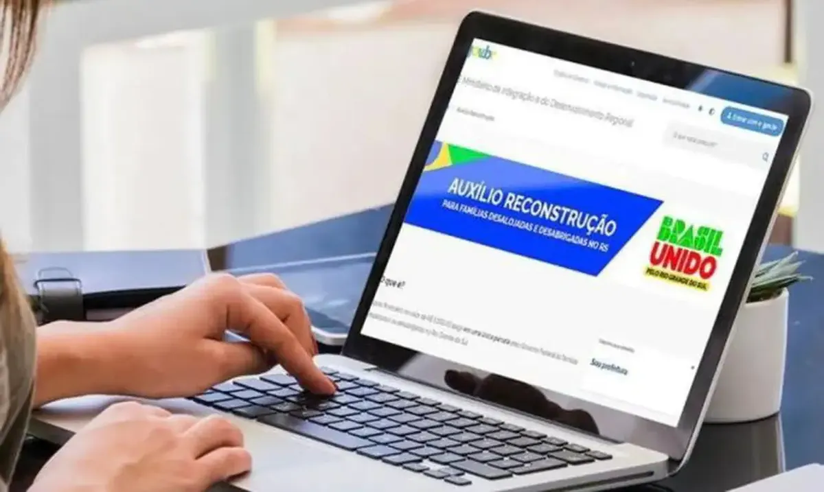 Pessoa acessando o site do Auxílio Reconstrução em um notebook para cadastramento.