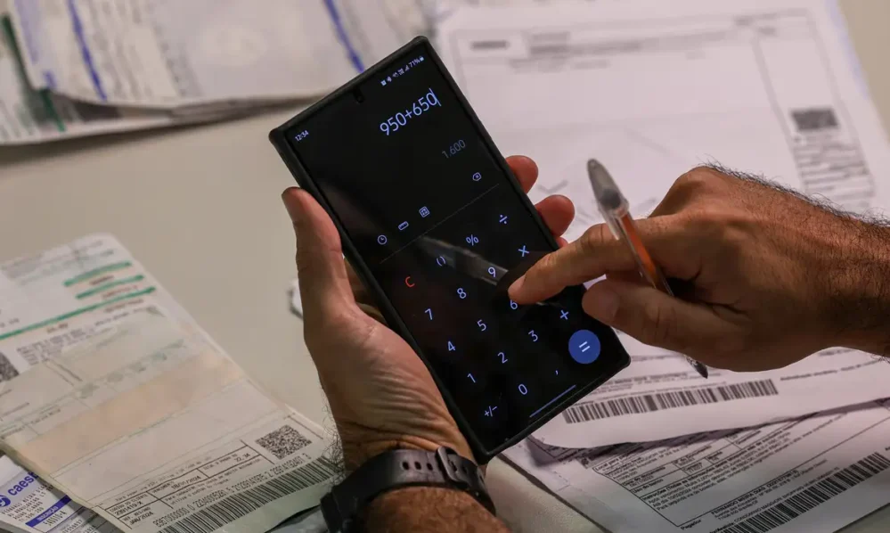 Consumidor utilizando uma calculadora no celular para simular o pagamento das dívidas durante a renegociação.