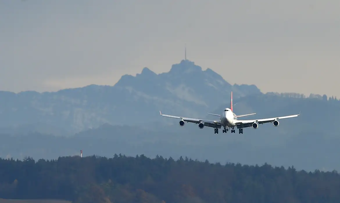 Avião aterrissando com montanhas ao fundo, simbolizando viagens facilitadas.