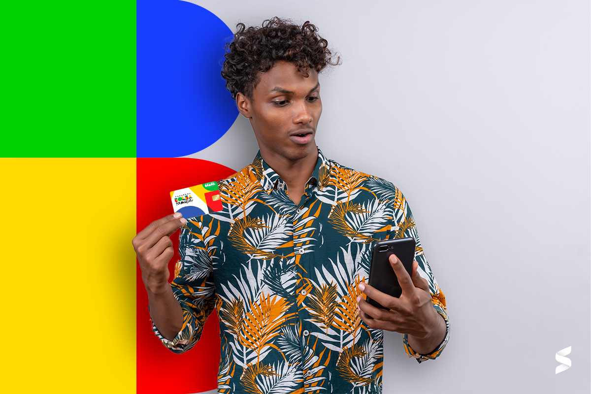 Homem segurando um cartão do Bolsa Família enquanto olha para o celular com expressão surpresa.