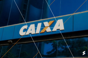 Logotipo da Caixa Econômica em fachada de agência, com letras brancas e laranja sobre fundo azul.