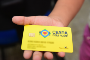 Cartão Ceará Sem Fome sendo exibido por um beneficiário, com o logo do programa.