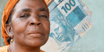 "Mulher idosa sorrindo com cédulas de 100 reais ao fundo, representando empoderamento financeiro."