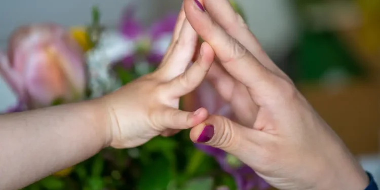 Mãe e criança tocando as mãos, simbolizando o apoio e a ajuda oferecida através do programa de auxílio.