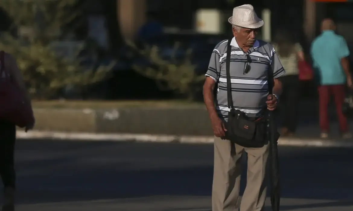 Aposentado caminhando pela rua, representando beneficiários do INSS que terão pagamentos antecipados.