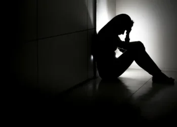 Mulher com expressão de preocupação sentada em um ambiente iluminado, simbolizando a importância da saúde mental e o apoio às pessoas com transtornos mentais.