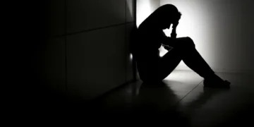 Mulher com expressão de preocupação sentada em um ambiente iluminado, simbolizando a importância da saúde mental e o apoio às pessoas com transtornos mentais.