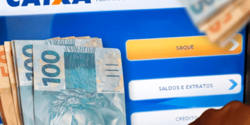 Tela de autoatendimento da Caixa Econômica Federal com opção de saque destacada e notas de dinheiro ao lado.