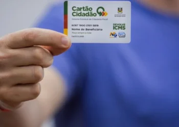 Imagem de um beneficiário segurando o Cartão de Cidadania do Devolve ICMS, usado para acessar os valores devolvidos pelo programa.
