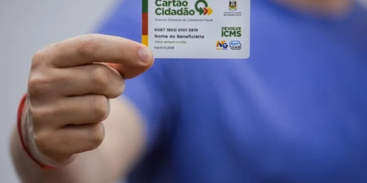 Imagem de um beneficiário segurando o Cartão de Cidadania do Devolve ICMS, usado para acessar os valores devolvidos pelo programa.