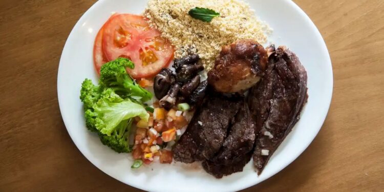 Prato de comida com carne, salada, farofa e legumes, representando o benefício do Cartão Alimentação.