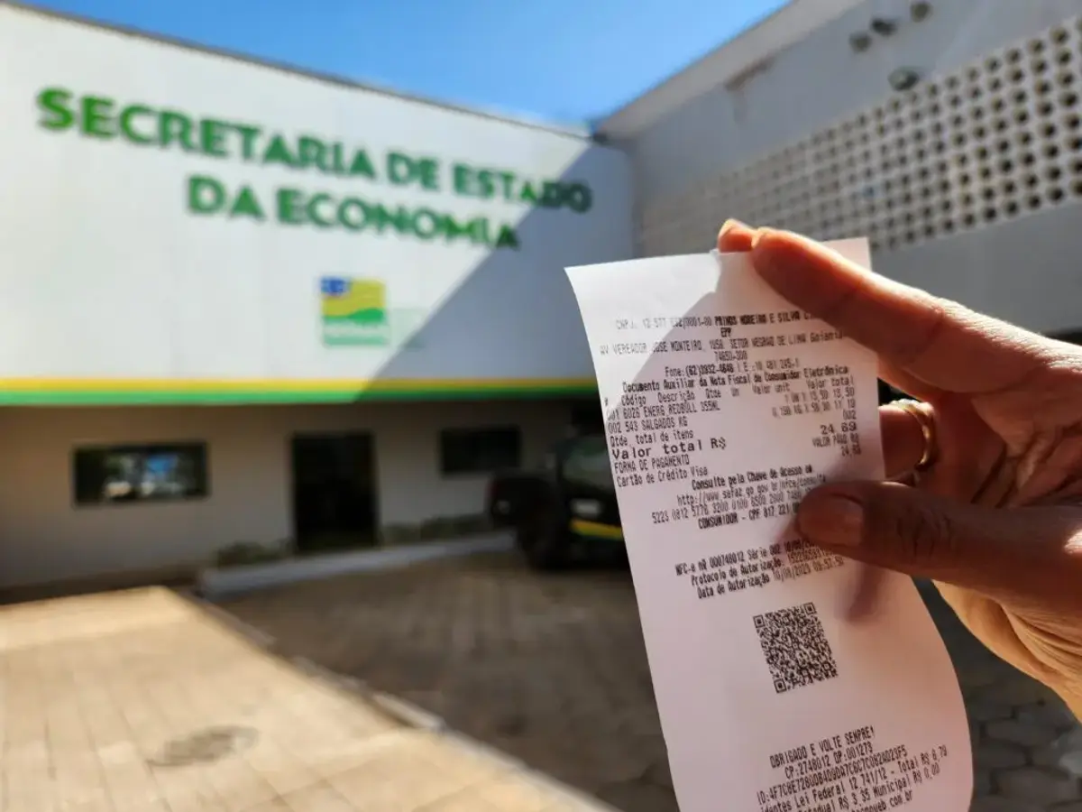 Pessoa segurando uma nota fiscal em frente à Secretaria da Economia para participar do sorteio.