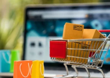 "Carrinho de compras com pacotes frágil ao fundo de um site de e-commerce."