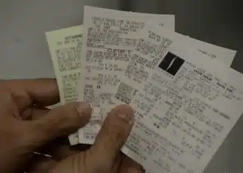 Pessoa segurando vários cupons fiscais, representando a participação no programa CPF na Nota.