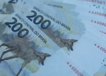 Notas de R$ 200,00 empilhadas, representando o impacto financeiro do aumento dos juros no crédito consignado do INSS.