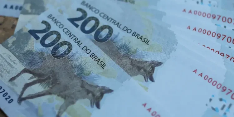 Notas de R$ 200,00 empilhadas, representando o impacto financeiro do aumento dos juros no crédito consignado do INSS.