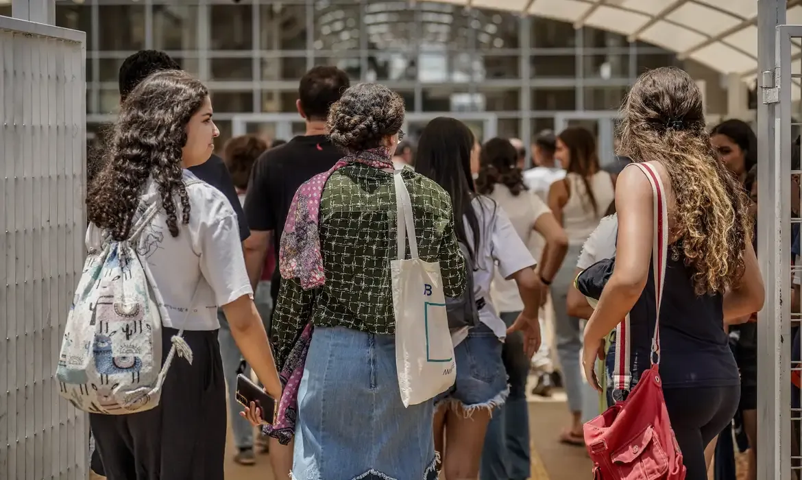 Os estudantes caminham em direção à instituição de ensino, destacando a importância da frequência escolar.