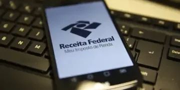 "Logo da Receita Federal no celular, com foco no aplicativo Meu Imposto de Renda, em fundo de teclado de computador."