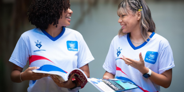 Estudantes com uniformes de escola pública conversam com livros nas mãos, celebrando a notícia sobre o pagamento de até R$ 150 do Cartão Escola 10, programado para a próxima segunda-feira.