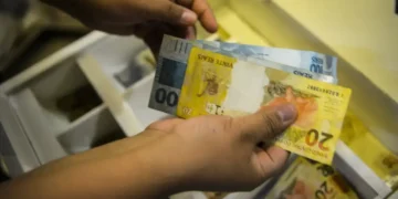 Notas de dinheiro sendo contadas, representando o saque dos valores esquecidos do PIS/Pasep.